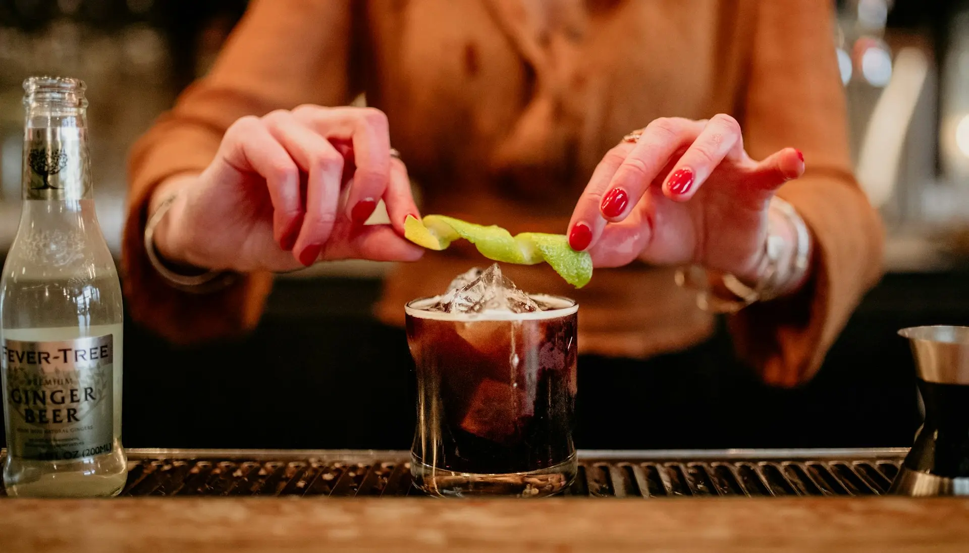 a woman holding a pickle over a drink